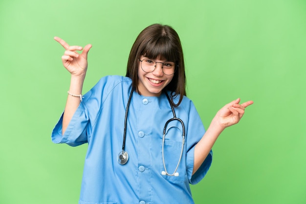 Petite fille en tant que médecin chirurgien sur fond isolé chroma key pointant le doigt vers les latéraux et heureux