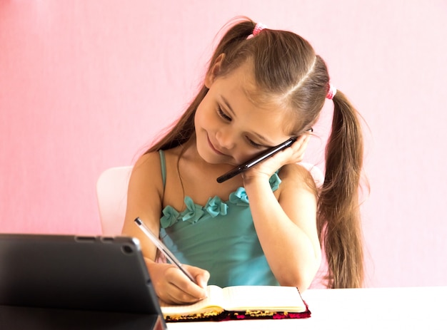 Petite fille avec téléphone et tablette à la table