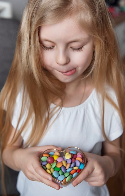 Petite fille tenant un bol de bonbons sucrés colorés