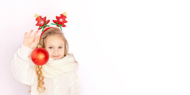 Petite fille tenant une boule de Noël rouge sur fond blanc isolé
