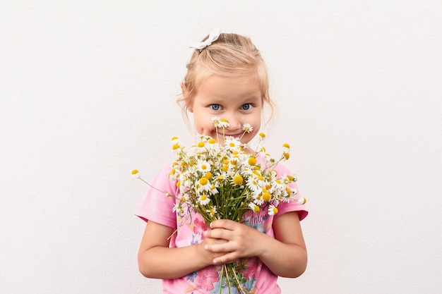 Petite fille tenant un bouquet de marguerites sur fond blanc