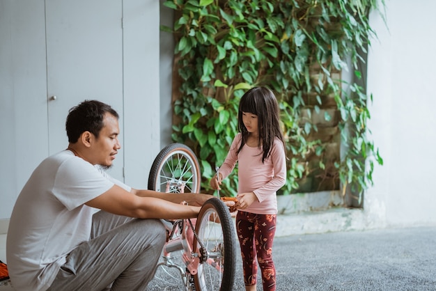 Petite fille tenant une clé en pédalant avec son père