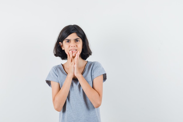 Petite Fille Tenant Les Doigts Sur Le Menton En T-shirt Et Regardant Pensif, Vue De Face.