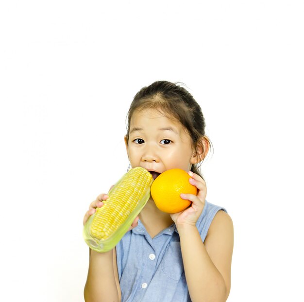 Petite fille tenant du maïs orange et sucré