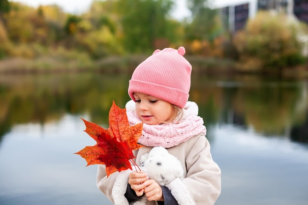 Petite fille tenant des feuilles d'érable rouges dans ses mains