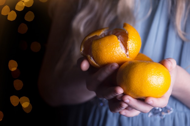 Petite fille tenant des mandarines dans ses mains. vacances de Noël