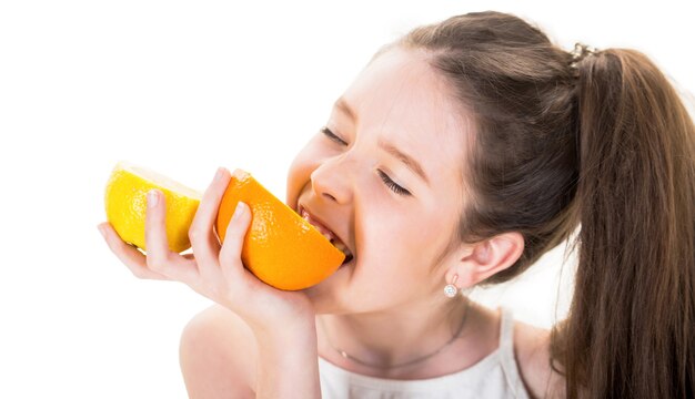 Petite fille tenant et mangeant des citrons. Adolescent tenant des agrumes orange. Belle petite fille aux oranges, citrons, pamplemousses, vitamine.