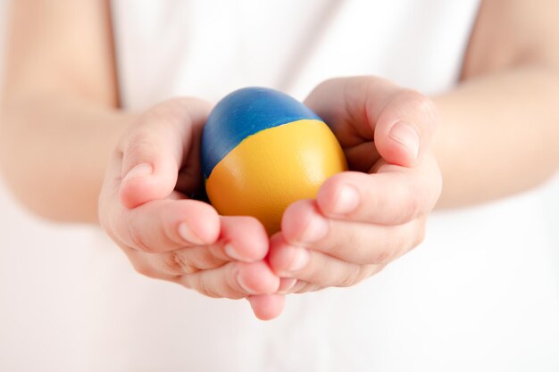 Petite fille tenant des oeufs de pâques sur fond bleu et jaune