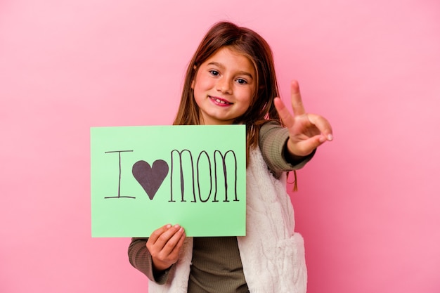 Petite fille tenant une pancarte j'aime maman isolée sur fond rose