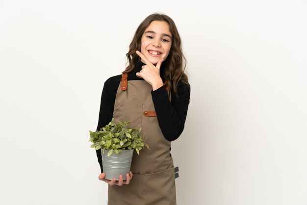 Petite fille tenant une plante isolée sur fond blanc heureux et souriant