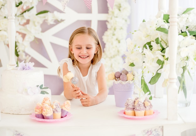 Petite fille tenant des sucettes sucrées colorées dans la barre de bonbons