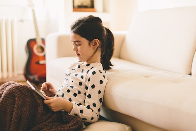 Petite fille tenant la tablette dans la chambre