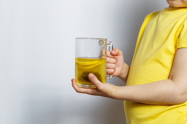 Petite fille tenant une tasse avec du thé au citron