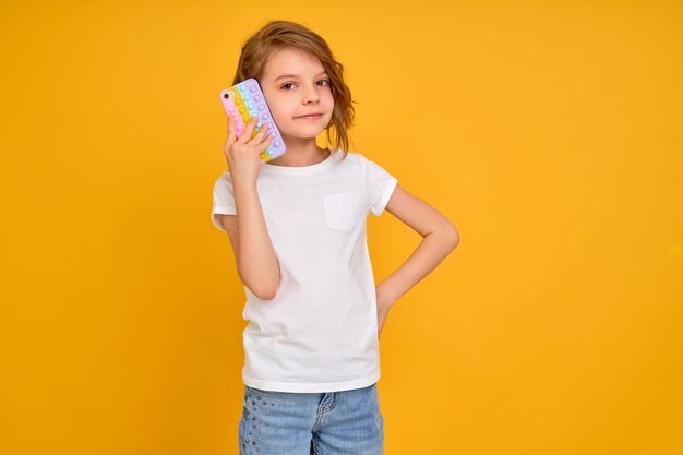 Petite fille tenant un téléphone isolé sur fond orange