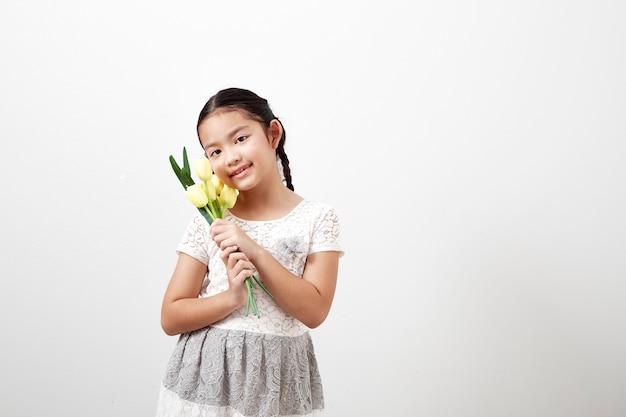 Petite fille tenant des tulipes jaunes sur blanc