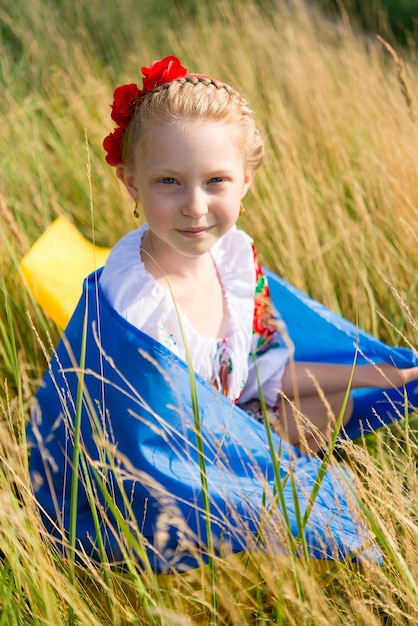 petite fille en tenue nationale ukrainienne - vyshyvanka. Ukraine, champ. Entre les mains du drapeau