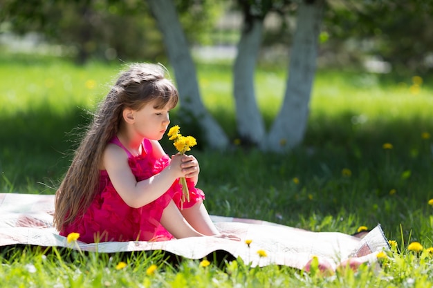 Une petite fille tient un bouquet de fleurs.