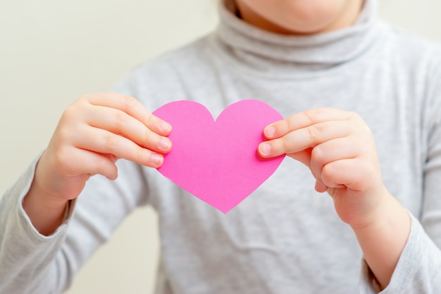 Petite fille tient coeur rose