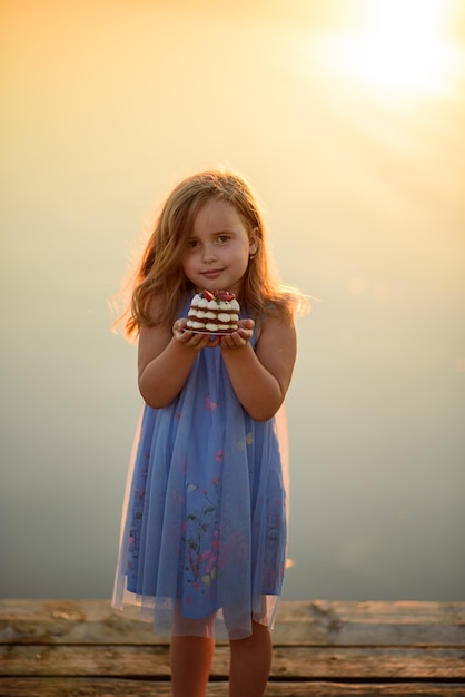 Une petite fille tient un dessert dans ses mains