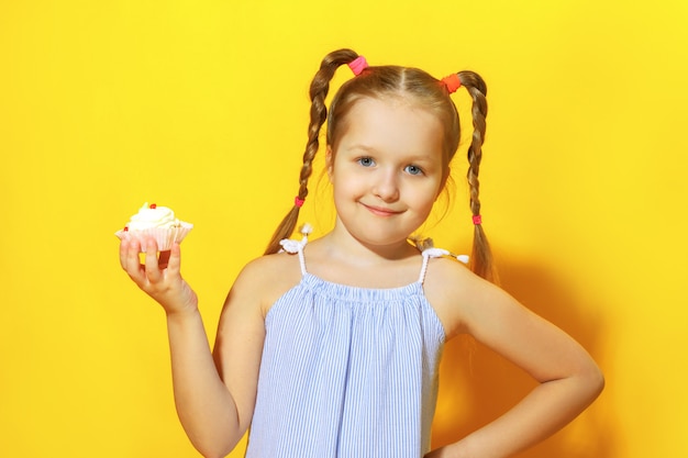 La petite fille tient un gâteau.