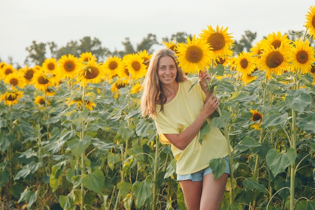 Une petite fille tient un gros tournesol en fleurs. Pétales de tournesol jaune. Un fond naturel associé à l'été. préparer la récolte