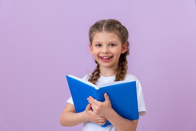 Une petite fille tient un livre et est heureuse.