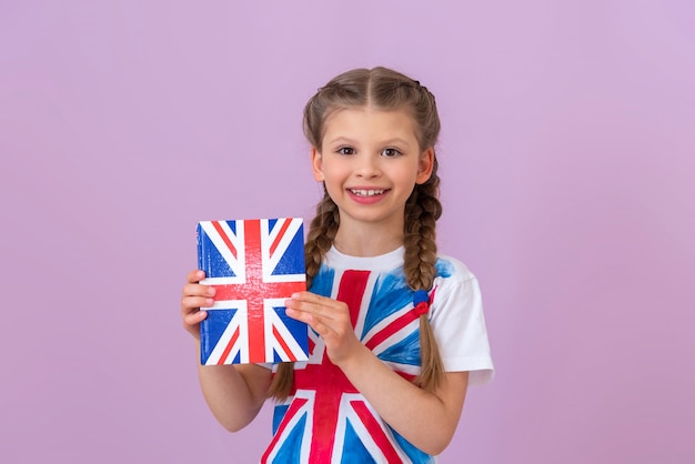 Une petite fille tient un manuel d'anglais dans ses mains.