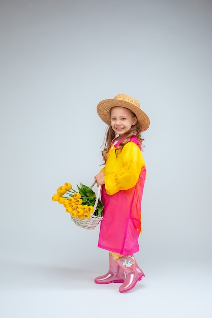 Petite fille tient un panier de fleurs