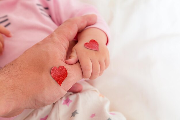 La petite fille tient papa par les coeurs du doigt pour le jour des parents ou la Saint-Valentin