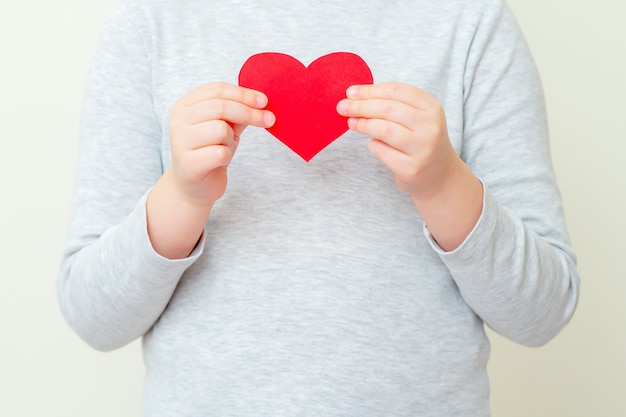 Petite fille tient un petit coeur rouge