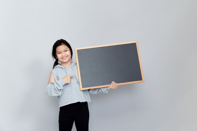 Une petite fille tient un tableau blanc