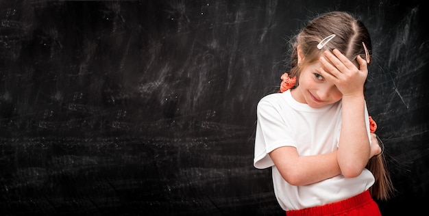 Petite fille touchant son front devant le tableau noir