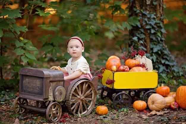 Photo petite fille en tracteur avec un chariot avec des citrouilles