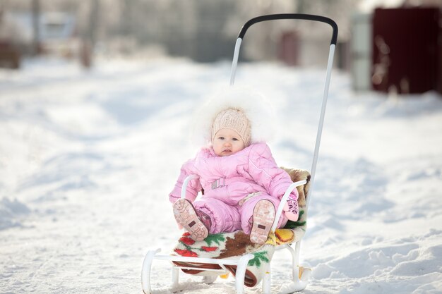 Petite fille sur un traîneau à pied d'hiver