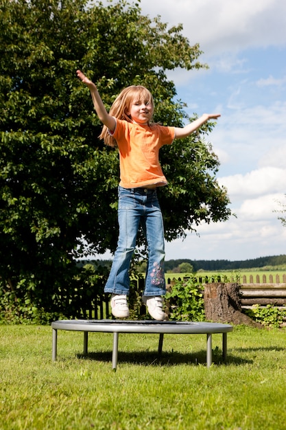 Petite fille sur un trampoline dans le jardin