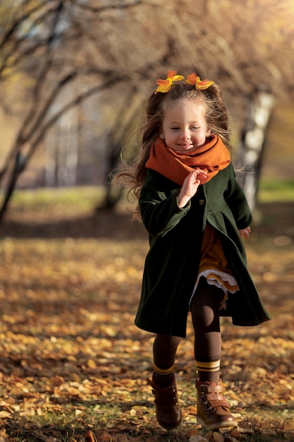 Une petite fille traverse le parc d'automne