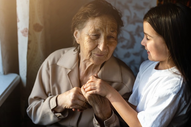 Petite fille et très vieille femme. Petit enfant étreignant la grand-mère. Petite fille