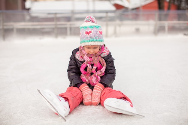 Petite fille triste assise sur une patinoire après la chute