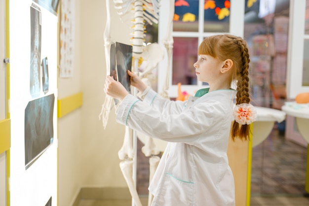 Petite fille en uniforme regarde la radiographie,