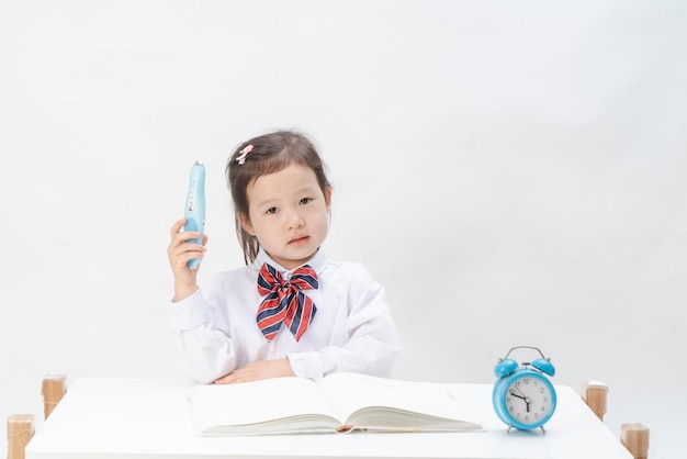 La petite fille en uniforme scolaire fait ses devoirs