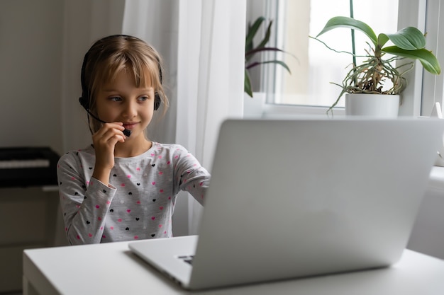 Petite fille utilisant le chat vidéo sur ordinateur portable à la maison. Espace pour le texte