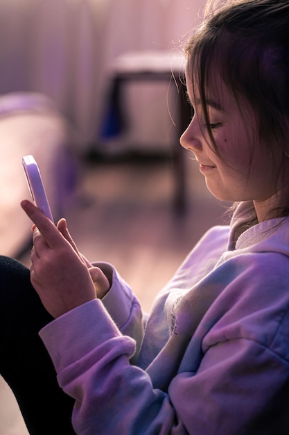 Une petite fille utilise un smartphone alors qu'elle est assise dans sa chambre