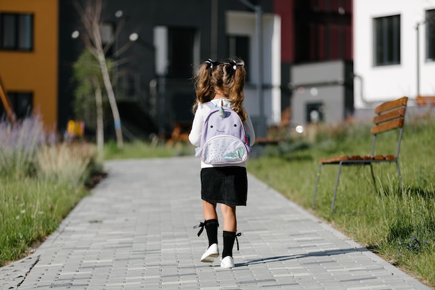 une petite fille va à l'école à travers le parc le long du chemin. notion d'enseignement à distance. écolière