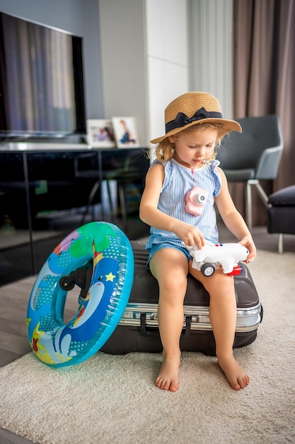 Petite fille avec valise bagages bagages et bouée de sauvetage gonflable jouant avec avion jouet et prêt