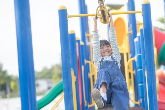 Une petite fille en vêtements décontractés jouant sur une aire de jeux pour enfants, tenant et grimpant. Mise au point sélective sur la tête de la fille.