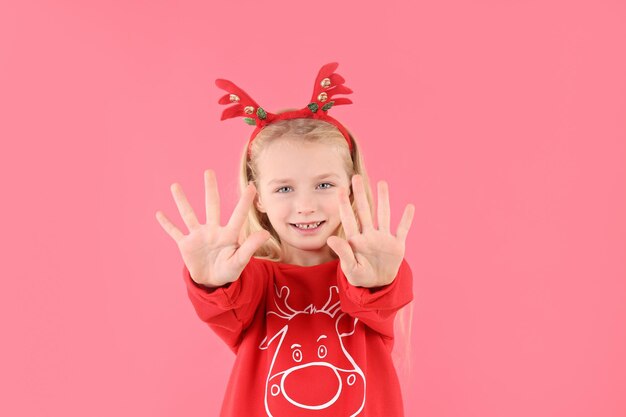 Petite fille en vêtements de Noël sur fond rose