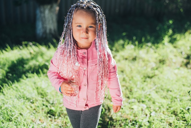 Une petite fille en vêtements roses avec des tresses afro roses