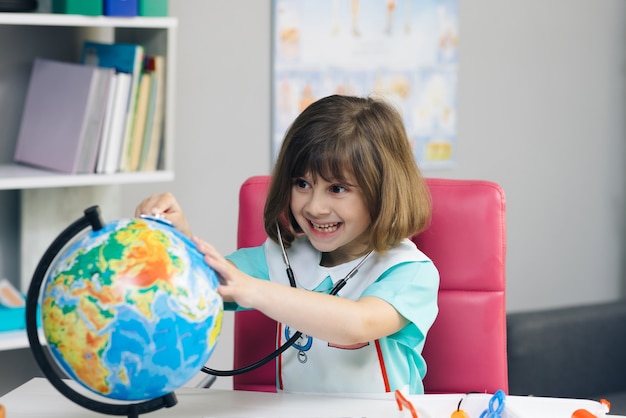 Une petite fille vêtue d'un costume de médecin mesure la température de la Terre.