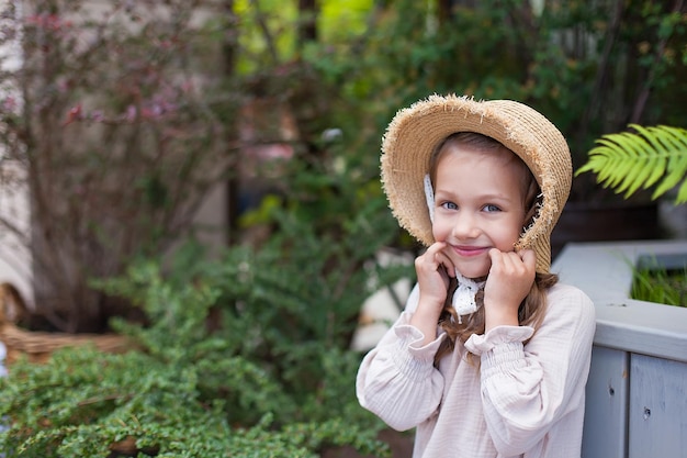 Une petite fille vêtue d'une robe d'été se tient sur un pont en bois dans le parc Une image avec des effets de bruit de mise au point sélective et une tonification Concentrez-vous sur la fille