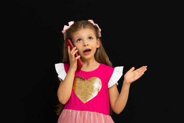 Petite fille vêtue d'une robe parlant au téléphone.